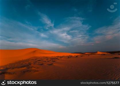 Lonely sand dunes under amazing evening sunset sky at drought desert landscape. Global warming concept