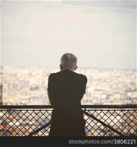 Lonely tourist man overlooks view Paris skyline, retro filter effect