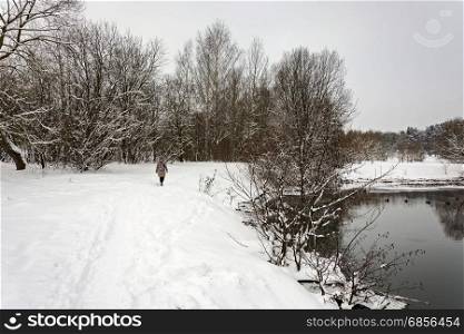 Lonely woman is walking on the bank of winter river