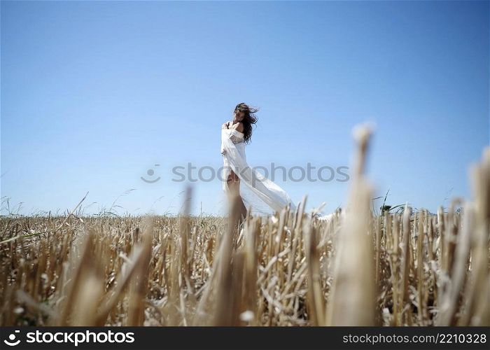 Lonely Woman With Long Wavy Hair, Dressed In A White Dress, Enjoys A Wheat Field At Sunset.