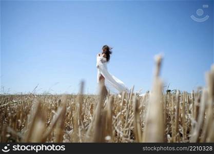 Lonely Woman With Long Wavy Hair, Dressed In A White Dress, Enjoys A Wheat Field At Sunset.