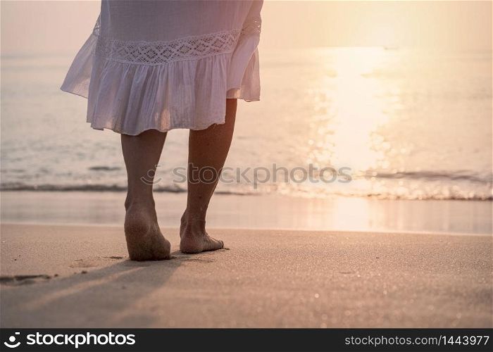 Lonely young asian woman standing on the beach at sunset
