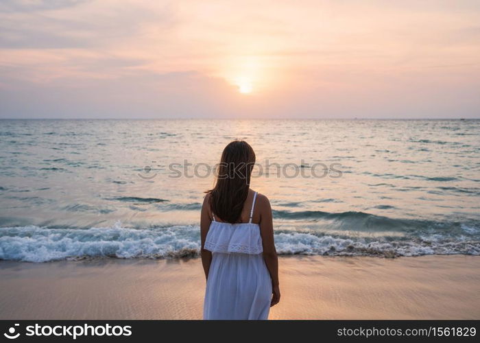 Lonely young asian woman standing on the beach at sunset