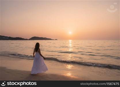 Lonely young asian woman standing on the beach at sunset