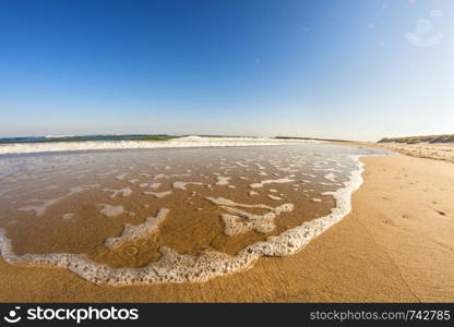 lonesome beach of the Baltic Sea with blue sky and surf