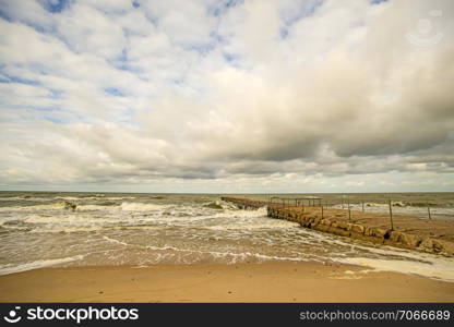 lonesome beach of the Baltic Sea with cloudy sky and surf