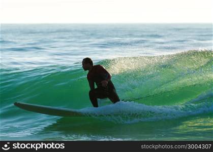 Long boarder surfing the waves at sunset in Portugal.