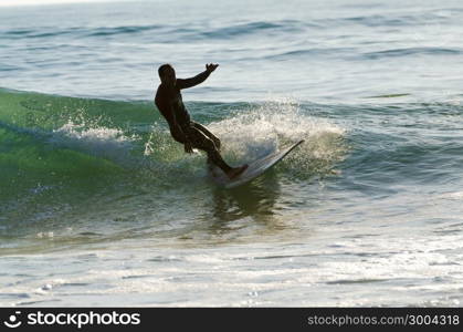 Long boarder surfing the waves at sunset in Portugal.