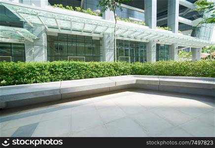Long concrete rest chair with modern office building background .