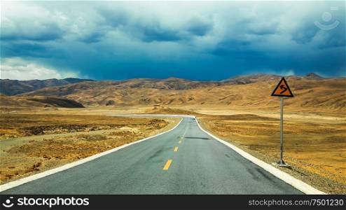 Long empty asphalt road in desert with clear cloudly sky .