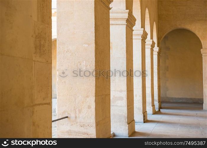 Long empty corridor with arch and stone columns in old building