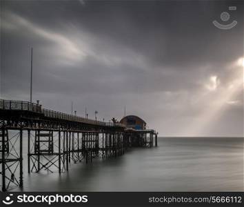 Long exposure landscape image of old pier stretching out to sea