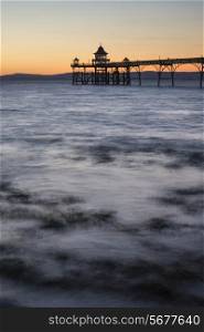 Long exposure landscape image of pier at sunset