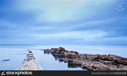 Long exposure moody dramatic seascape with rocks and motion blur