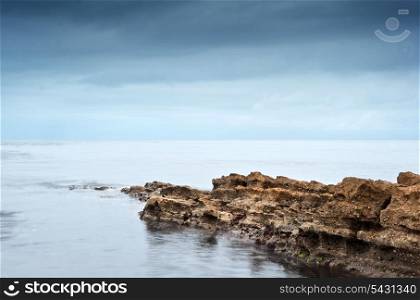Long exposure moody dramatic seascape with rocks and motion blur