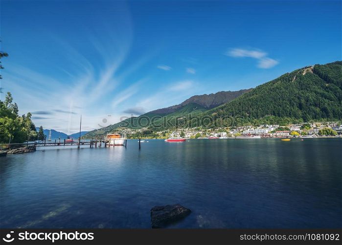 Long-exposure shot of Queenstown lakefront city center at Lake Wakapitu, the famous lake of Queenstown, center of tourism, water sport and boat tours, South Island of New Zealand.