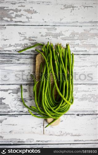 Long green beans on white wooden background