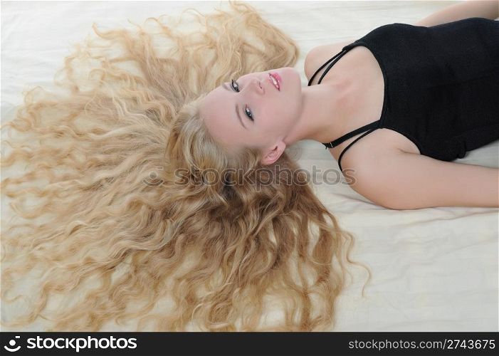 Long-haired young blonde woman lying on the bed