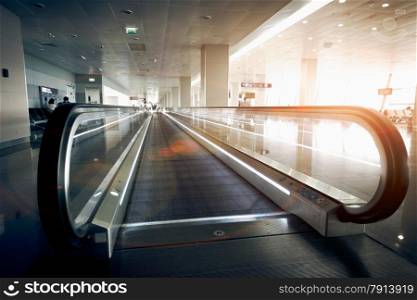 Long horizontal escalator at modern airport terminal at sun light