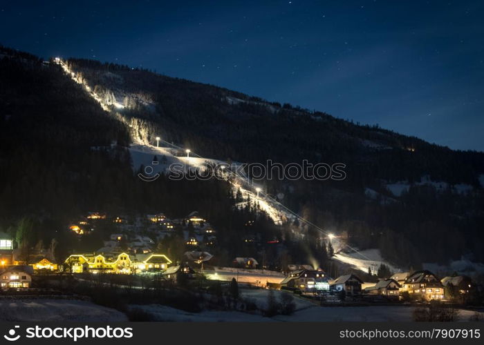 Long illuminated ski slope at Austrian Alps at starry night