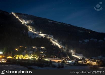 Long illuminated ski slope at Austrian Alps at starry night