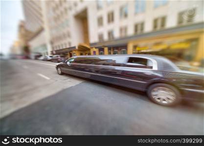 Long Limousine speeding up along city street.