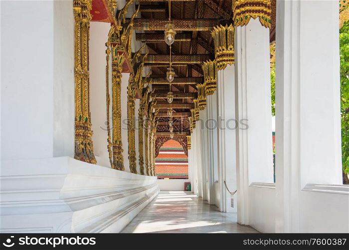 Long ornate corridor with white marble columns and gold lanterns. Temple of Emerald Buddha, Bangkok, Thailand