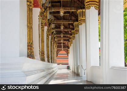 Long ornate corridor with white marble columns and gold lanterns. Temple of Emerald Buddha, Bangkok, Thailand