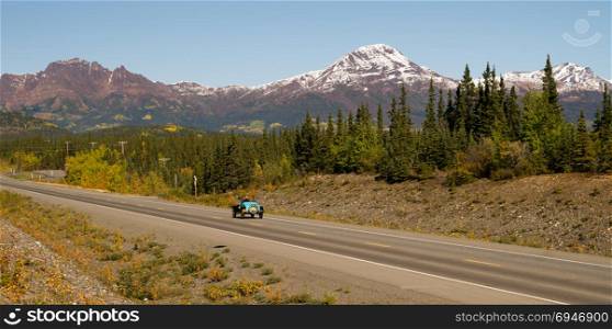 Long panoramic vintage car moves along north Alaska highway North America