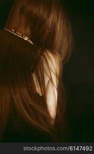 Long red hair of young girl on black background
