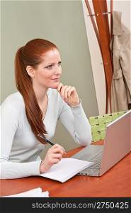 Long red hair woman working at office with laptop sitting at table