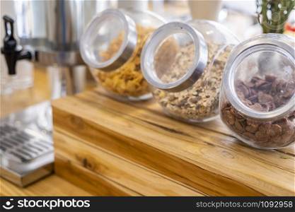 Long row Glass jars with breakfast cereal at on the dining table decoration at buffet self service at hotel.