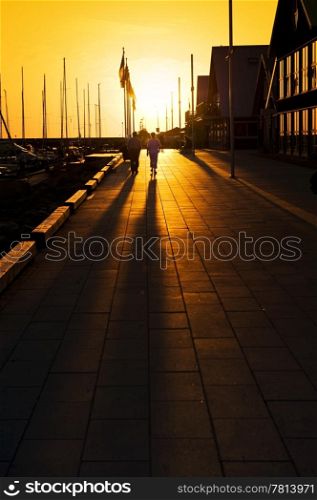 Long shadows on a marina promenade on a summer evening