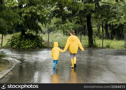 long shot mother son holding hands while wearing rain coats