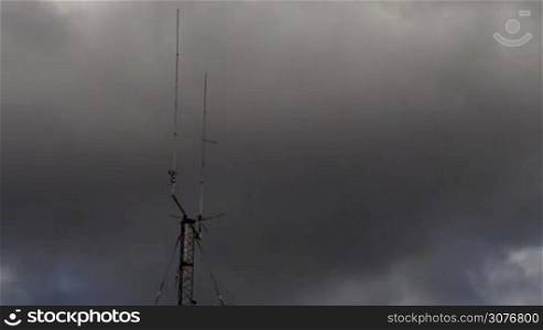 Long shot of a Home based dual spike Telecommunications antenna tower with storm clouds time lapse with no birds in it.