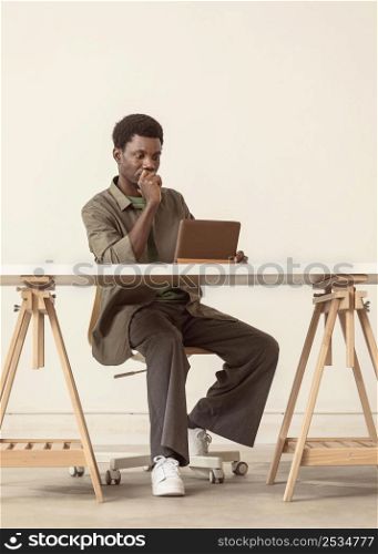 long shot person sitting working laptop