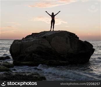long shot woman standing big rock ocean