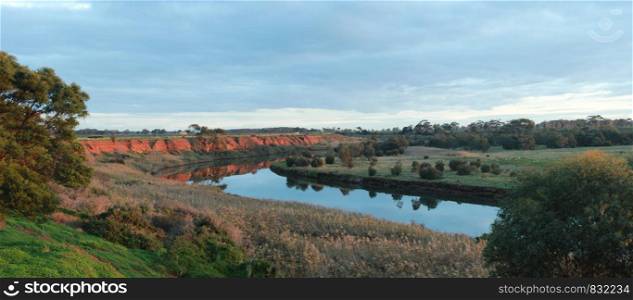 long stretching bend in a river that flows past red rock cliffs and into the ocean at Werribee south during golden hour, Victoria, Australia