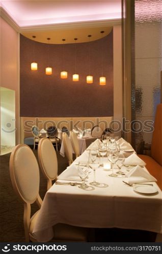 Long table in restaurant with place settings.