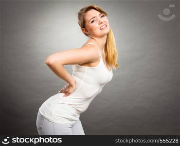Long working hours and health. Young female with backache. Woman suffering from back pain on gray. Woman suffering from back pain