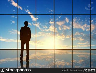Long working hours. Silhouette of businessman against panoramic office window
