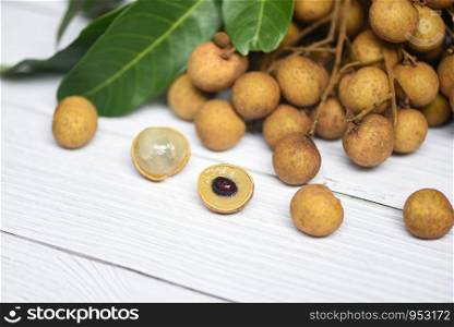 Longan fresh tropical fruit and green leaf in Thailand / Dimocarpus longan and peel exotic fruits on white wooden background