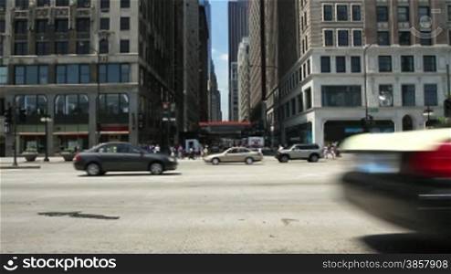 Looking across a street in the City of Chicago, with traffic passing in front of camera.