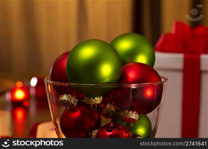 Looking at a glass vase filled with Christmas red and green ornaments.
