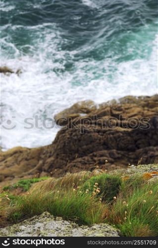 Looking down a cliff onto stormy ocean at the rocky coast of Brittany, France