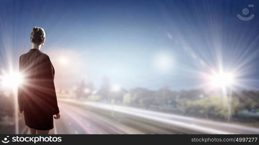 Looking for one&rsquo;s way. Back view of businesswoman standing on road and looking far away