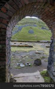 Looking through arch of ruin to valley of Cwmystwyth, remains of lead mining. Ceredigion, Wales, United Kingdom, Europe.