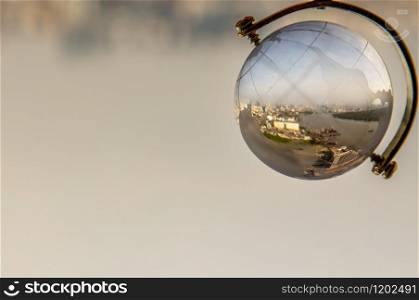 Looking through crystal globe showing city skyline. Refraction photography. Selective focus
