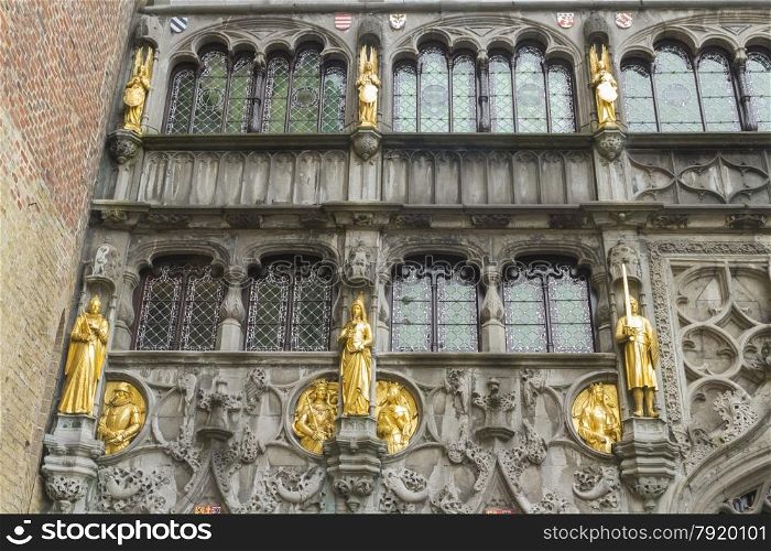 Looking up at medieval guilded statues and windows of the Basilica of the Holy Blood. Burg Square, Bruges, West Flanders, Belgium, Europe