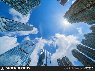 Looking up at modern office buildings. Financial district and business centers in smart city for technology background. Skyscraper and high-rise buildings in Hong Kong at noon with blue sky.